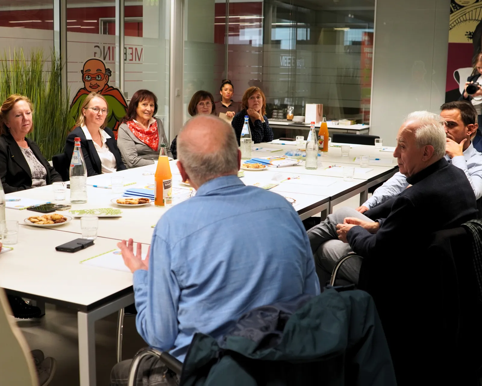 Discussion autour de la table entre bénévoles et invités lors de la visite du Ministre Max Hahn au service Super Senior du MEC asbl