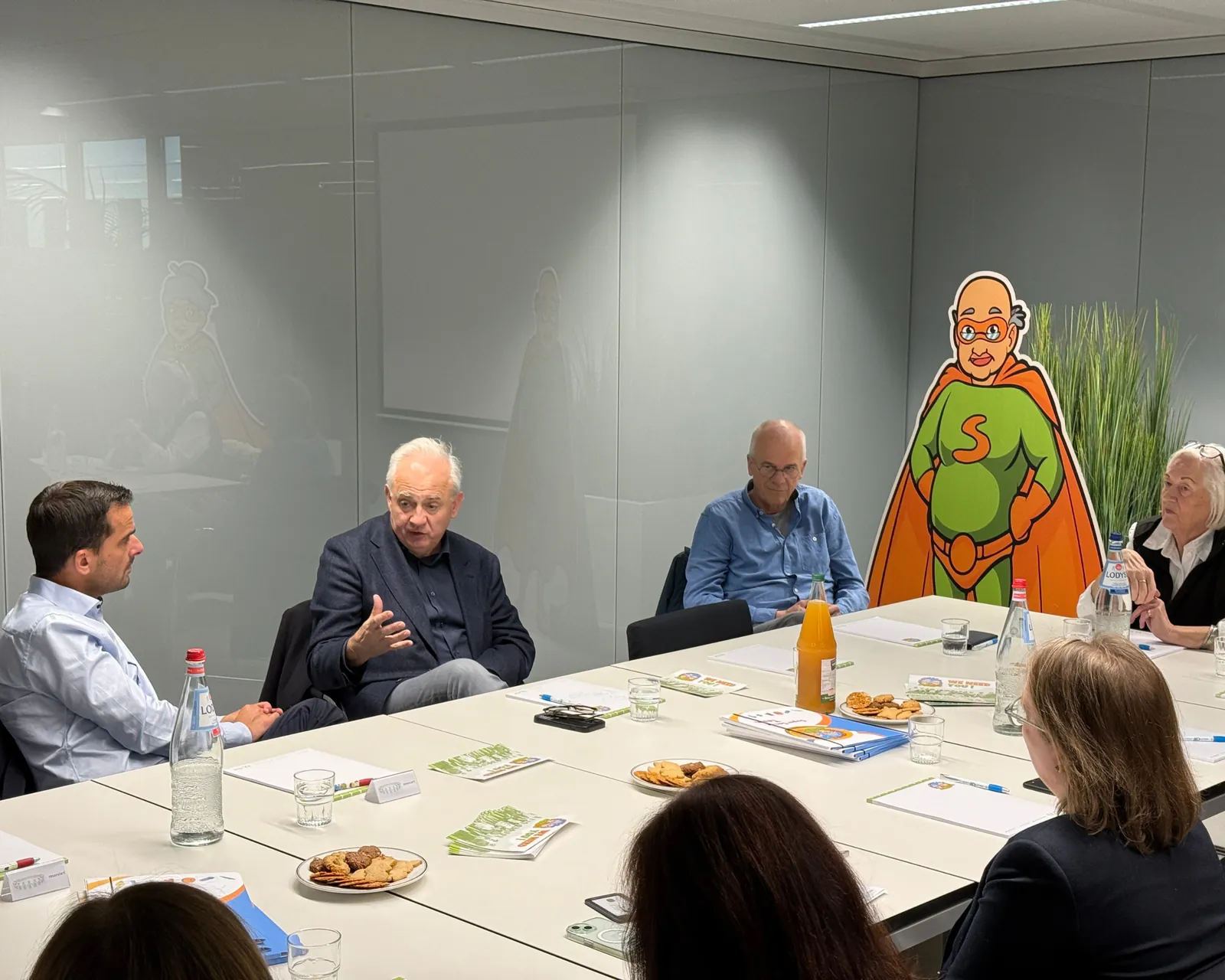 Table ronde avec les invités et la mascotte Super Senior lors de la visite du Ministre Max Hahn au service Super Senior du MEC asbl