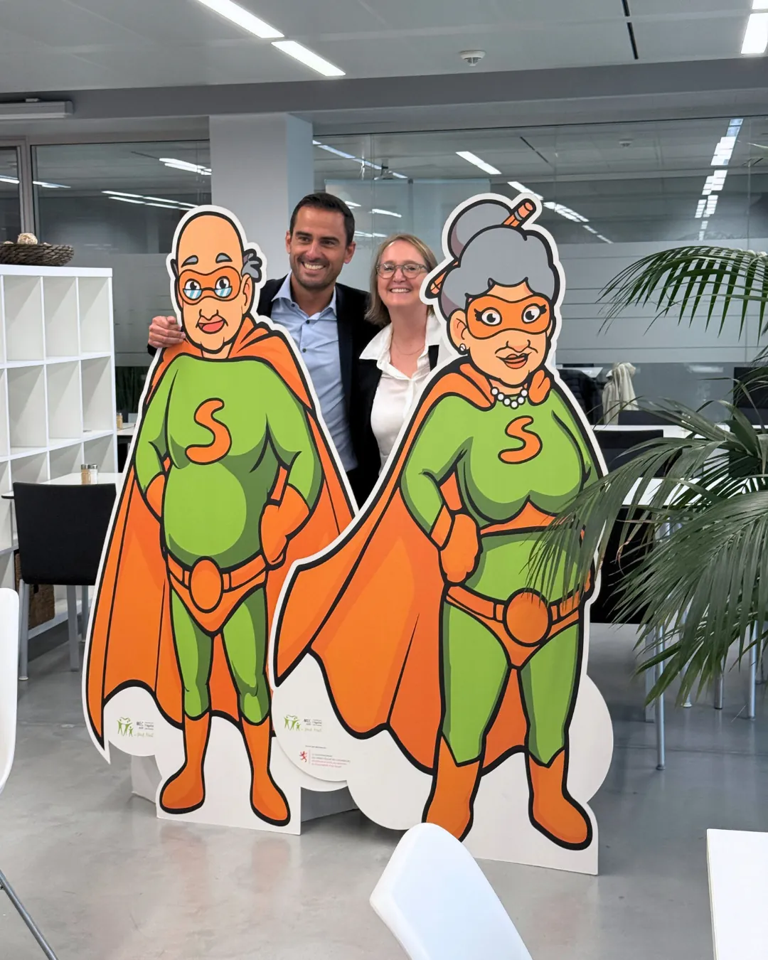 Invités posant avec les mascottes Super Senior lors de la visite du Ministre Max Hahn au service Super Senior du MEC asbl
